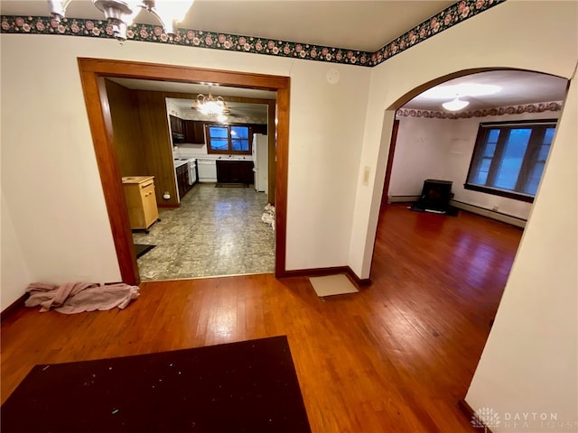 corridor with a notable chandelier, a baseboard heating unit, and hardwood / wood-style floors