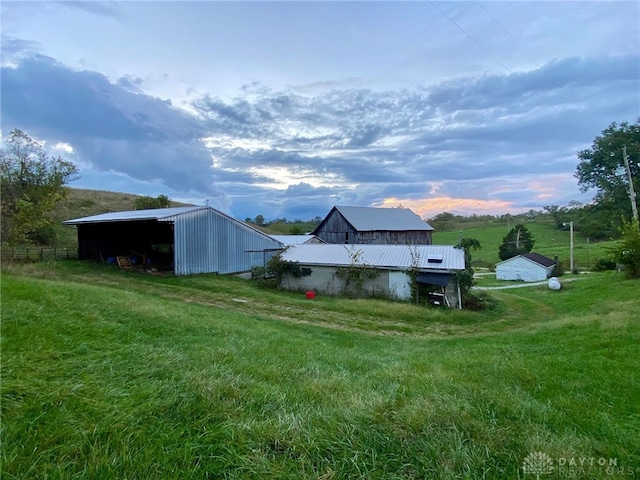 yard at dusk featuring a rural view and an outbuilding