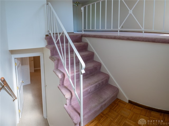 staircase featuring parquet floors