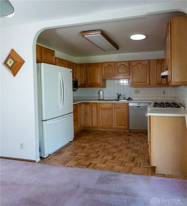 kitchen with stainless steel appliances, light parquet floors, tasteful backsplash, and sink