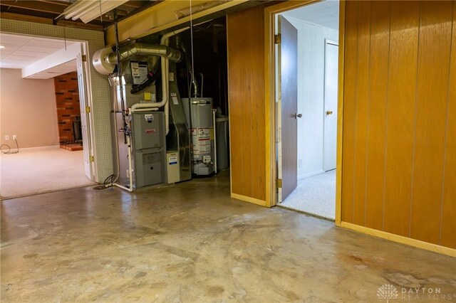 basement with heating unit, water heater, and wooden walls