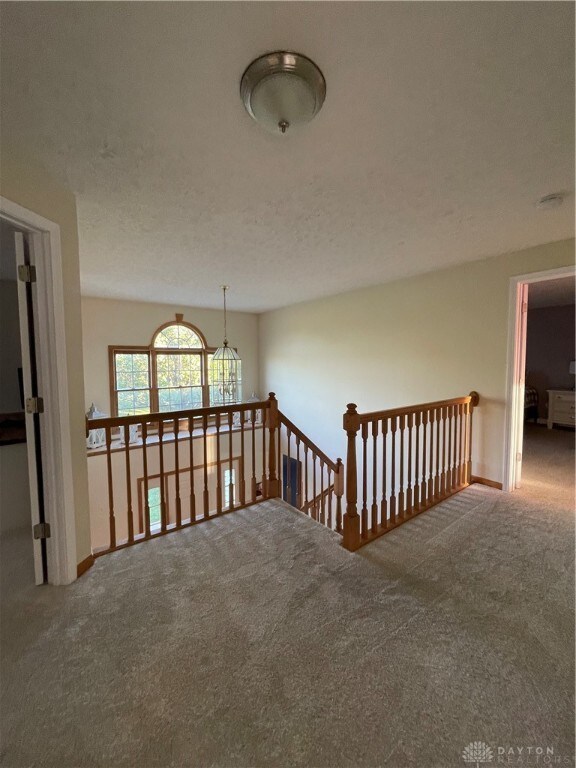 hall featuring a textured ceiling and carpet