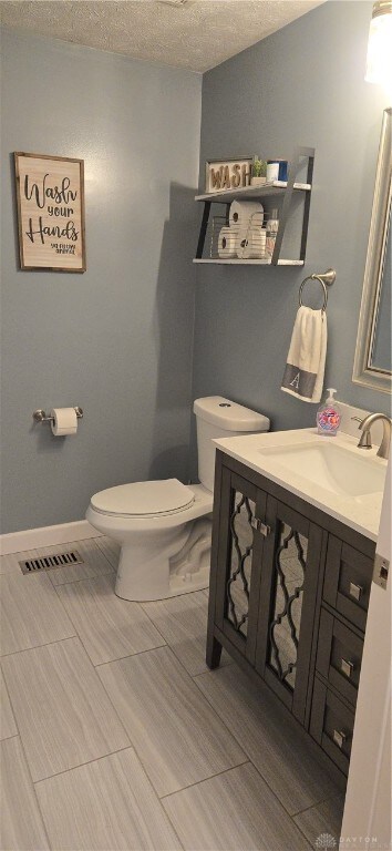 bathroom with vanity, a textured ceiling, and toilet