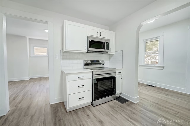 kitchen featuring stainless steel appliances, white cabinets, plenty of natural light, and light wood-type flooring