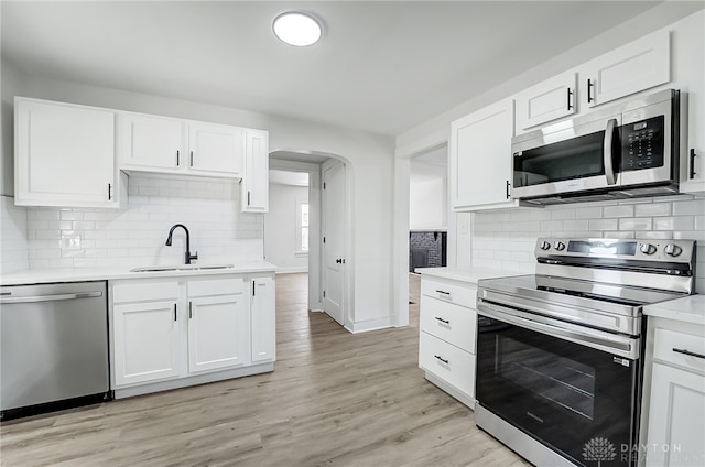 kitchen featuring white cabinets, appliances with stainless steel finishes, light wood-type flooring, and sink