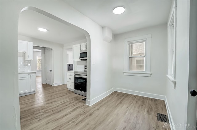 kitchen with light hardwood / wood-style flooring, stainless steel appliances, white cabinets, and backsplash