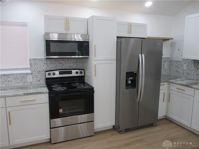 kitchen with stainless steel appliances, backsplash, light hardwood / wood-style floors, and white cabinetry