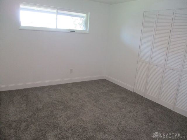 unfurnished bedroom with dark carpet and a closet