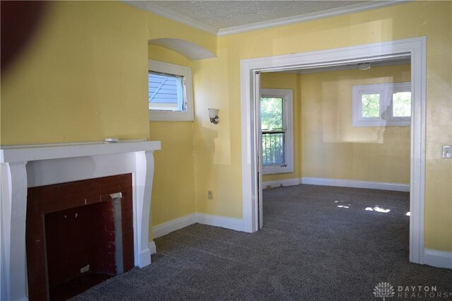 unfurnished living room with a fireplace, a textured ceiling, dark carpet, and crown molding