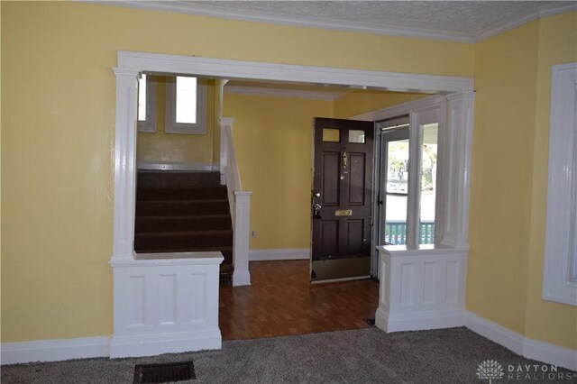 carpeted foyer with crown molding and a textured ceiling