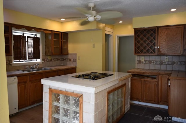 kitchen featuring dishwasher, backsplash, electric cooktop, sink, and tile counters