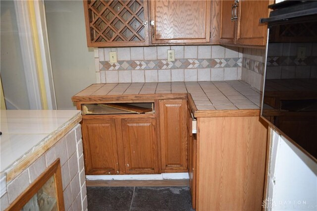 kitchen featuring backsplash, tile countertops, and dark tile patterned flooring