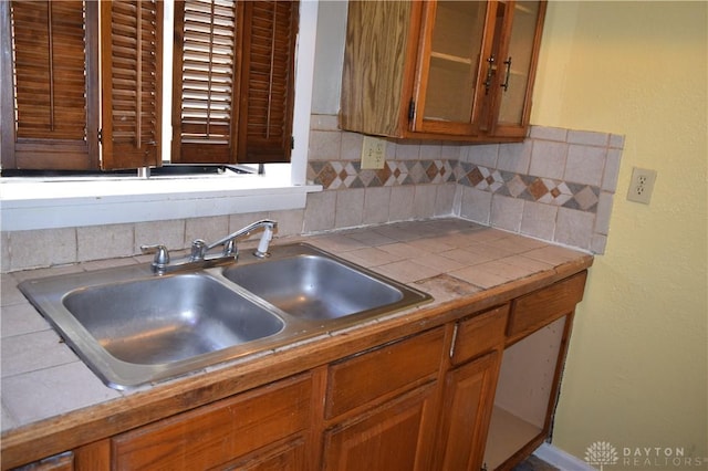 kitchen featuring decorative backsplash, tile counters, and sink