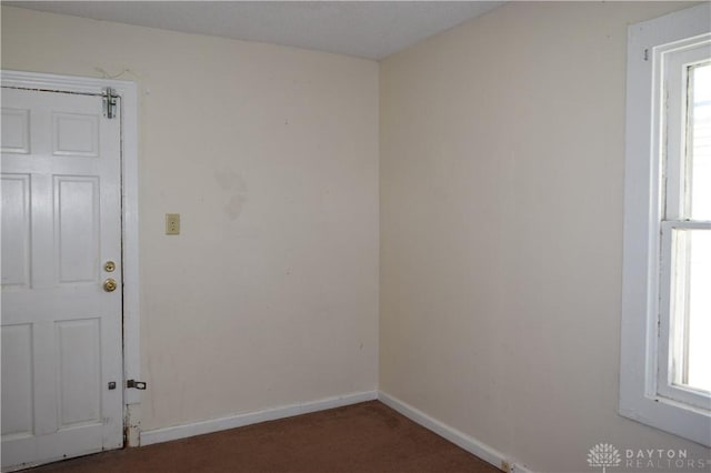 unfurnished room featuring dark colored carpet