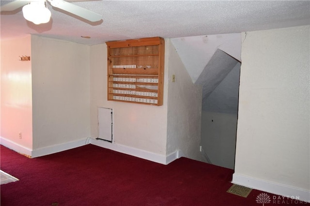 carpeted spare room with a textured ceiling, vaulted ceiling, and ceiling fan