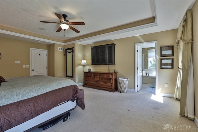 bedroom with light colored carpet, a raised ceiling, ceiling fan, and ensuite bathroom