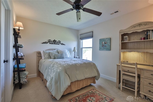 bedroom with ceiling fan, light colored carpet, and a textured ceiling