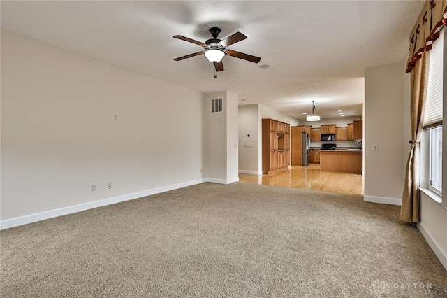 unfurnished living room featuring ceiling fan and light colored carpet