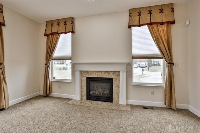 unfurnished living room featuring a tiled fireplace and carpet