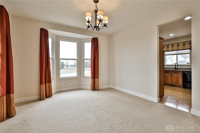 carpeted empty room featuring sink, a notable chandelier, and a textured ceiling