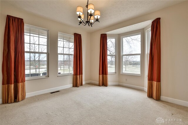 unfurnished room with a notable chandelier, light colored carpet, and a textured ceiling