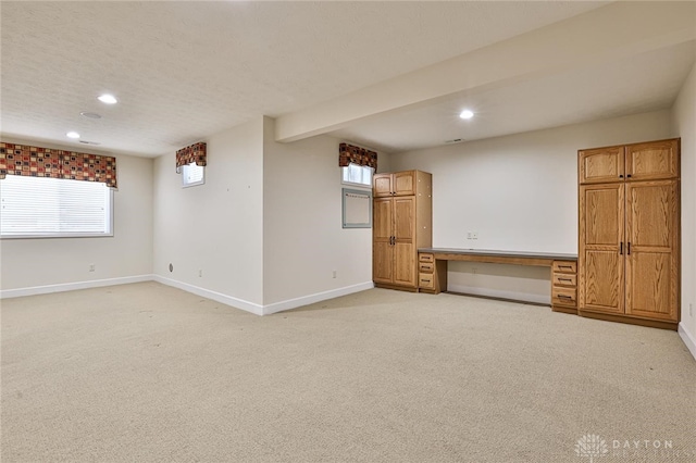 interior space with light colored carpet, built in desk, and a textured ceiling