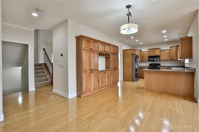 kitchen featuring pendant lighting, black appliances, sink, kitchen peninsula, and light hardwood / wood-style flooring