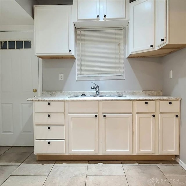 kitchen featuring white cabinetry, light stone countertops, sink, and light tile patterned floors