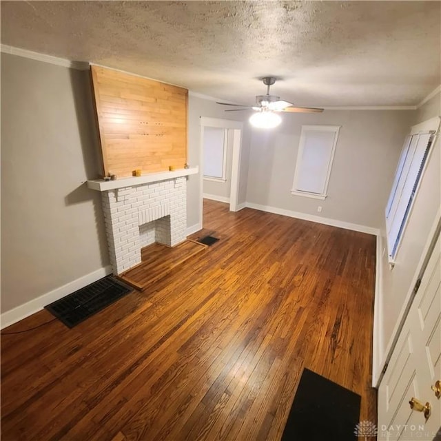 unfurnished living room featuring ornamental molding, a textured ceiling, ceiling fan, a fireplace, and hardwood / wood-style floors