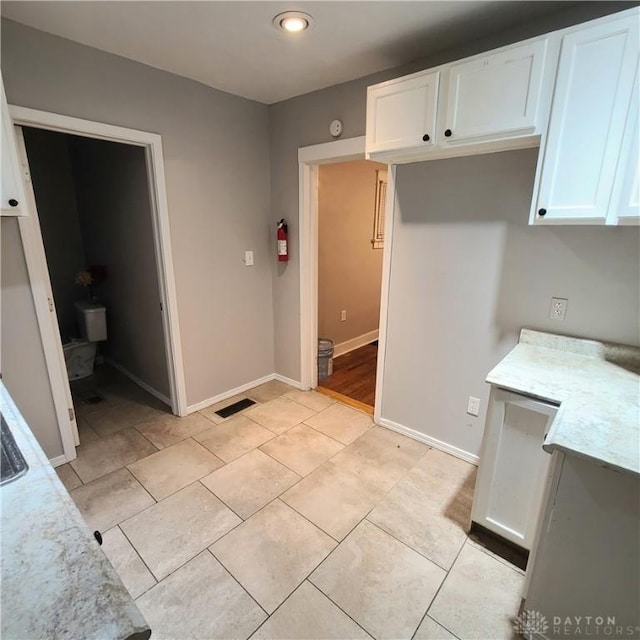 kitchen with light tile patterned flooring and white cabinetry