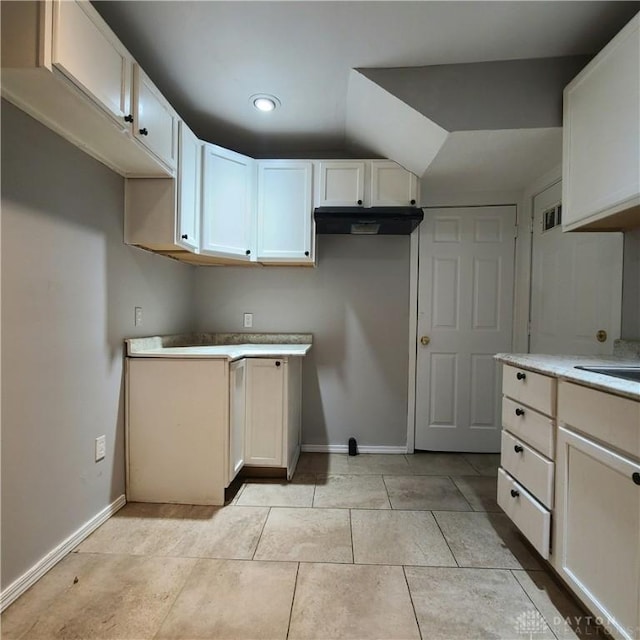 kitchen featuring light tile patterned floors, white cabinetry, and lofted ceiling