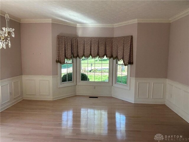 spare room featuring light hardwood / wood-style flooring, plenty of natural light, and ornamental molding