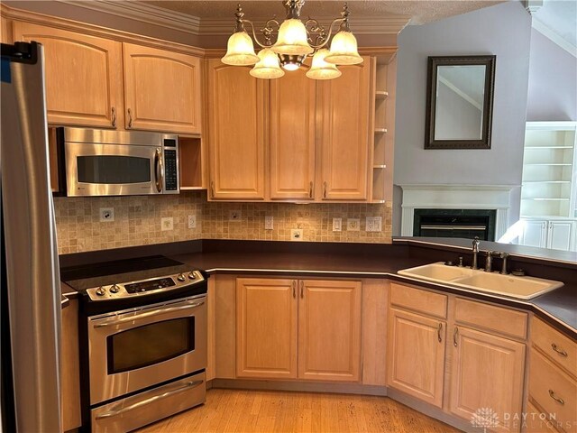 kitchen with stainless steel appliances, tasteful backsplash, sink, pendant lighting, and light hardwood / wood-style flooring