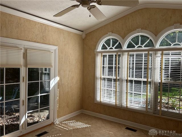 entryway with ceiling fan, lofted ceiling, ornamental molding, a textured ceiling, and tile patterned floors