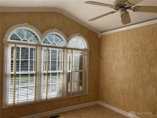 tiled empty room featuring ceiling fan, a textured ceiling, crown molding, and vaulted ceiling