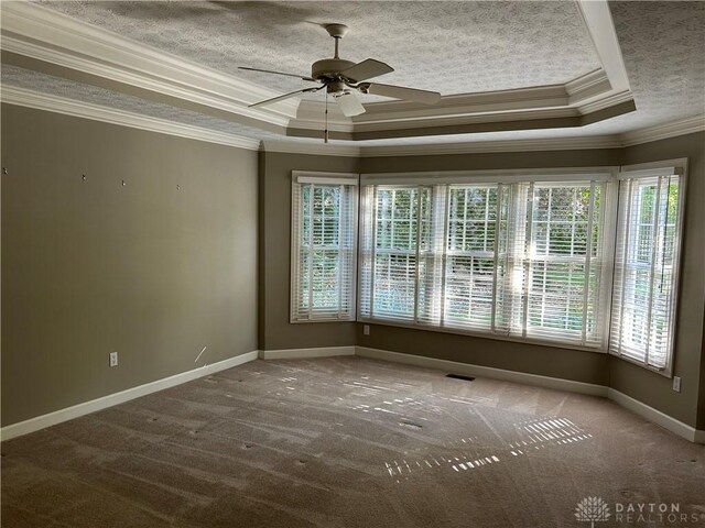 carpeted empty room featuring ceiling fan, a raised ceiling, plenty of natural light, and crown molding