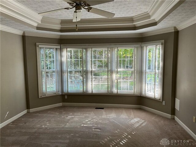 carpeted empty room featuring ceiling fan, a tray ceiling, and crown molding