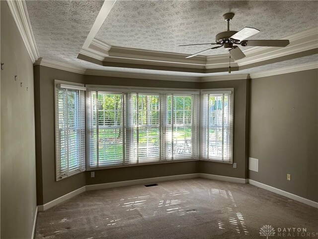 unfurnished room with carpet floors, a tray ceiling, ornamental molding, and ceiling fan