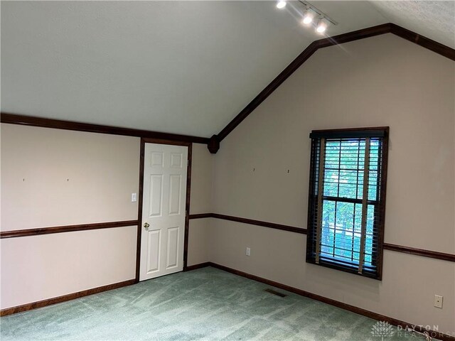 carpeted empty room with vaulted ceiling