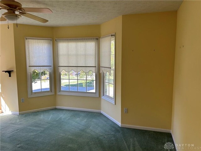 carpeted empty room featuring ceiling fan and a textured ceiling