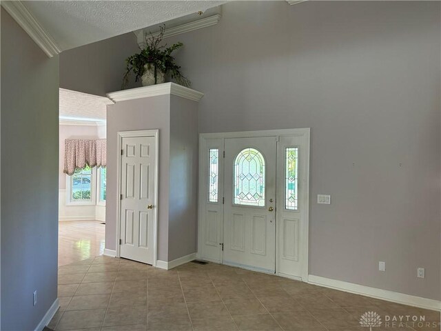 tiled foyer entrance with plenty of natural light, crown molding, high vaulted ceiling, and a textured ceiling