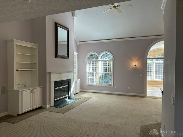 unfurnished living room featuring lofted ceiling, ceiling fan, light carpet, crown molding, and a textured ceiling