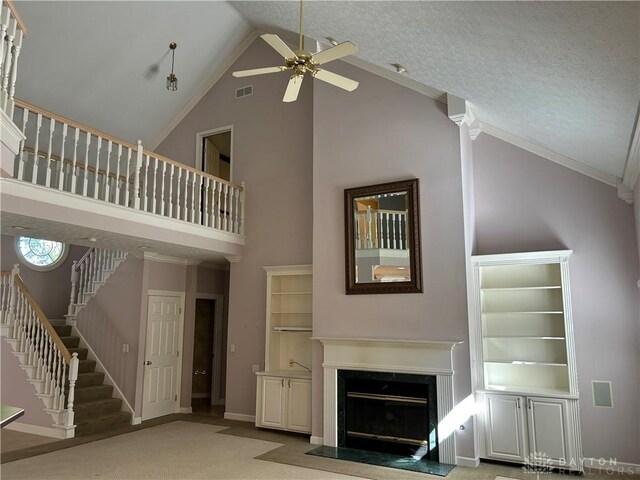 unfurnished living room featuring high vaulted ceiling, ceiling fan, carpet floors, ornamental molding, and a textured ceiling