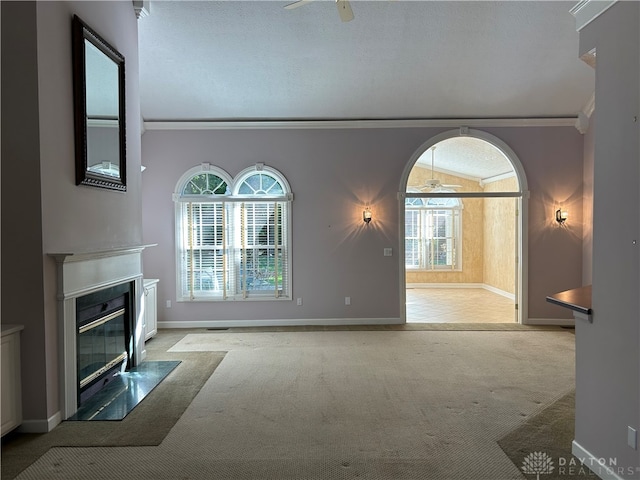 unfurnished living room featuring ornamental molding, light carpet, a wealth of natural light, and a textured ceiling