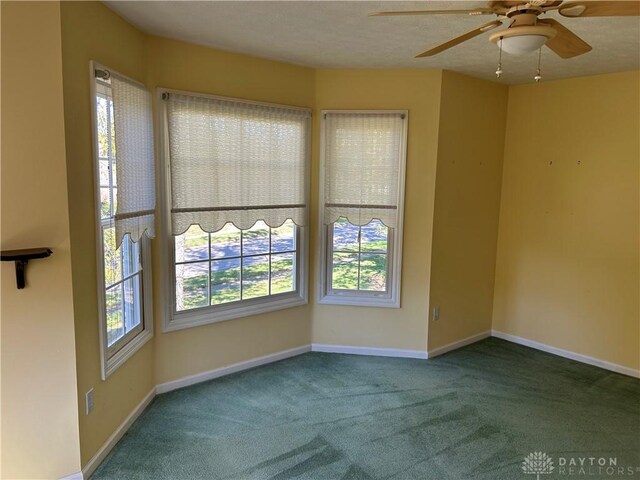 carpeted spare room featuring ceiling fan, a textured ceiling, and a healthy amount of sunlight