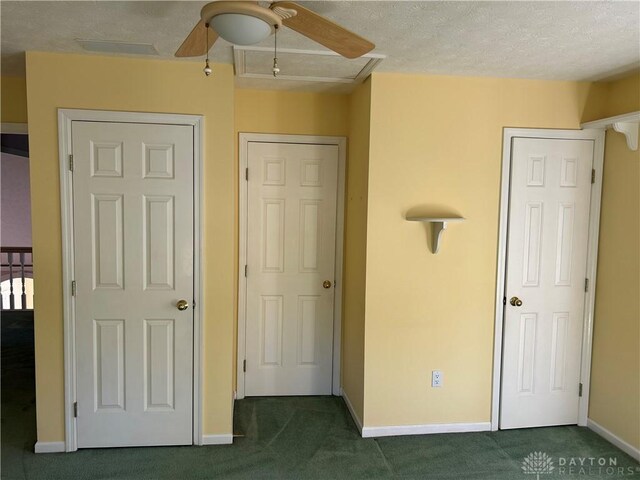 unfurnished bedroom featuring dark carpet, a textured ceiling, and ceiling fan