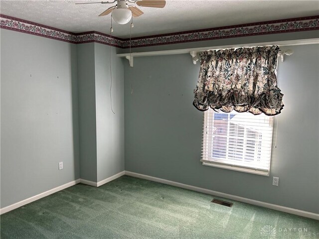 empty room featuring ceiling fan, carpet flooring, and a textured ceiling