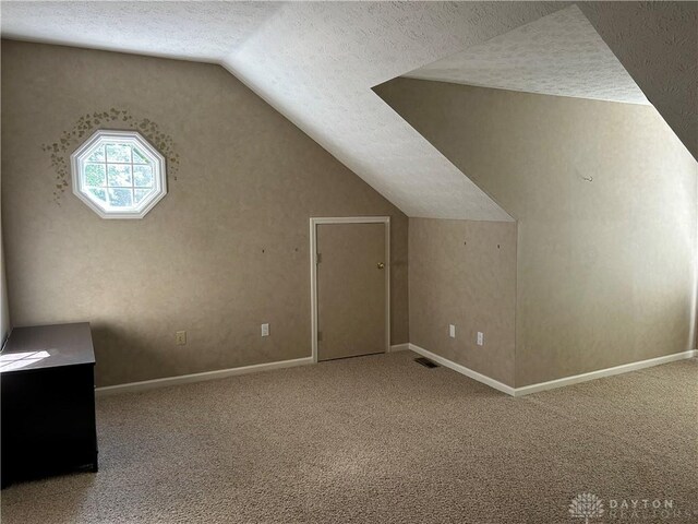 bonus room with a textured ceiling, lofted ceiling, and carpet