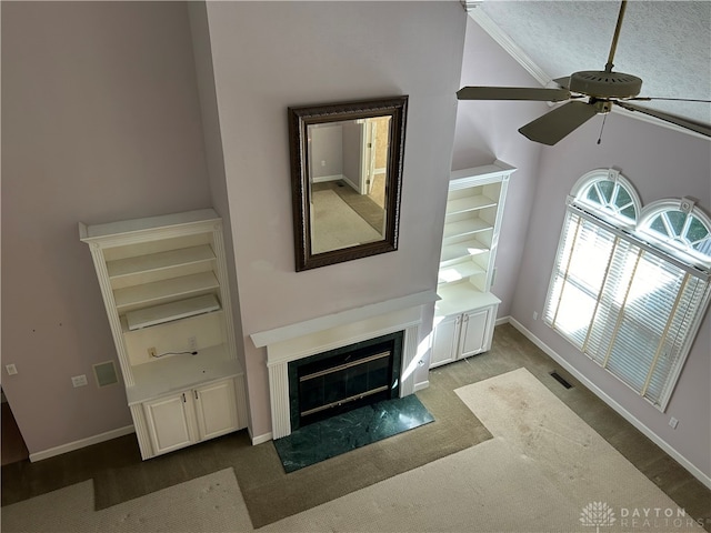 unfurnished living room featuring ceiling fan, dark colored carpet, a high end fireplace, built in features, and ornamental molding