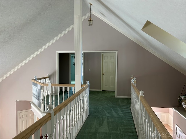 corridor with crown molding, dark colored carpet, a textured ceiling, and vaulted ceiling